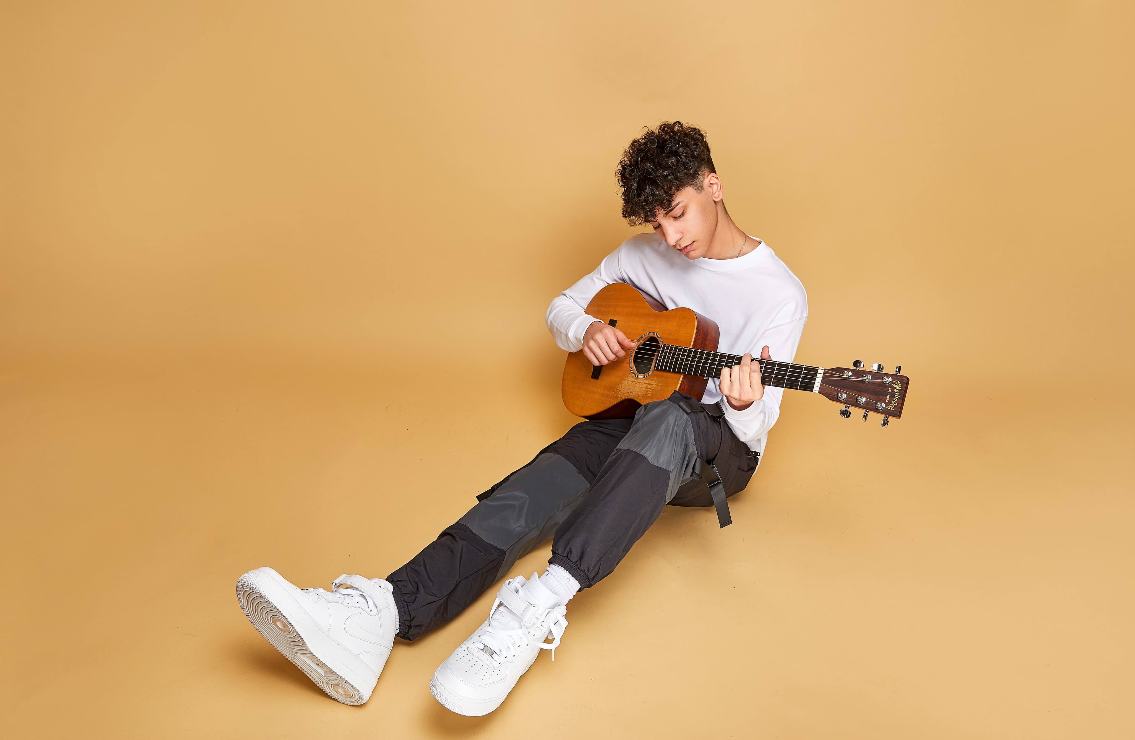 Adam playing acoustic guitar in a warm golden studio
